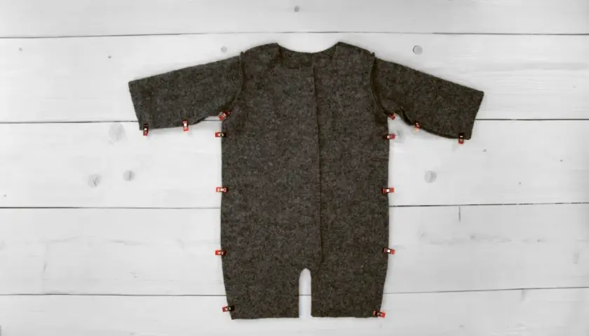 Graues Overall-Schnittmuster, bereit zum Nähen, mit roten Klammern fixiert. Ein tolles, **overall schnittmuster kostenlos** Projekt für DIY-Fans.