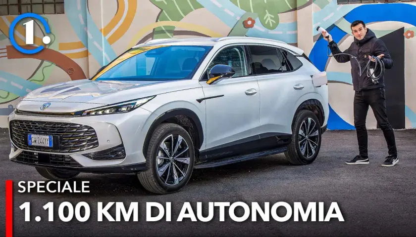Un uomo con cavo di ricarica accanto a un MG HS Hybrid+ bianco, pronto per un viaggio di 1.100 km.
