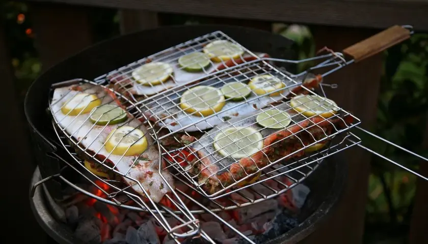 Grilla abborre med citron och lime på en kolgrill. Doften sprider sig i sommarkvällen.