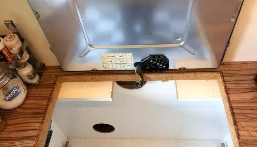 Beim Kochfeld ausbauen wird die elektrische Verbindung gelöst. Kabel und Anschlussklemmen sind sichtbar.