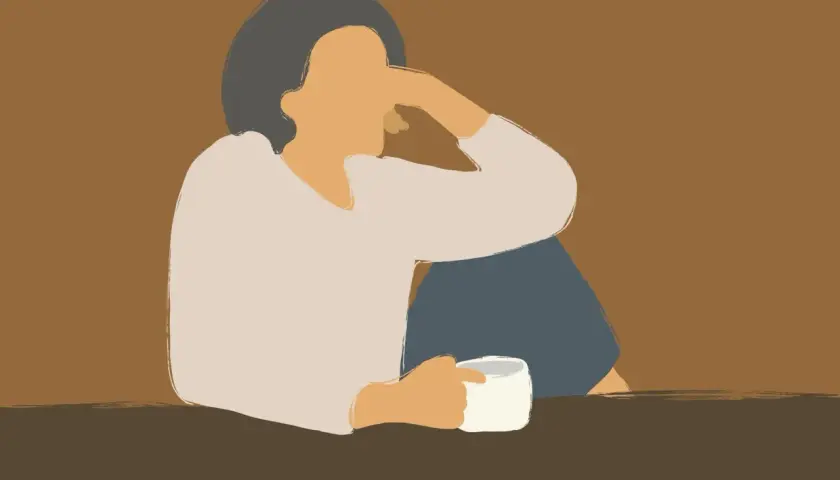 Eine Person sitzt allein mit einer Tasse Kaffee, die Arme um die Knie geschlungen. Die Haltung und der Ausdruck deuten auf eine lieblose Ehe im Alter hin, voller Einsamkeit.