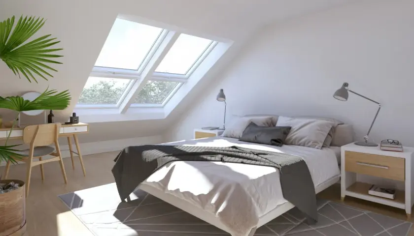 Luminosa camera da letto con finestre sul tetto che inondano di luce naturale il letto accogliente e la zona toeletta.