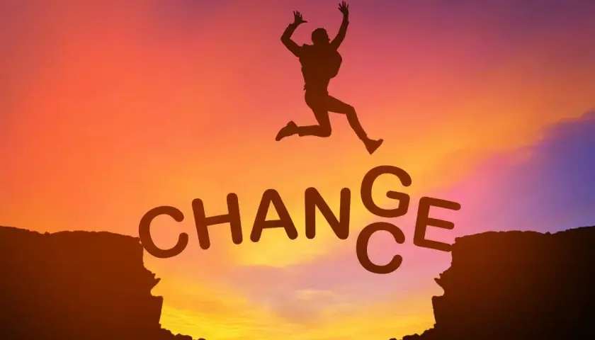 Sylwetka skacze przez przepaść, nad napisem "CHANGE". Jak mówiły Oprah Winfrey cytaty, zmiana jest kluczem do rozwoju.