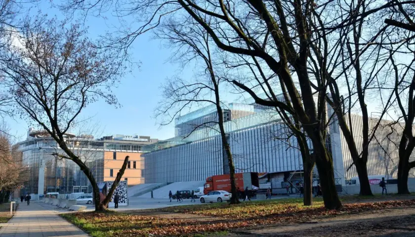 Nowoczesny budynek Centrum Spotkania Kultur na placu teatralnym w Lublinie, otoczony drzewami.
