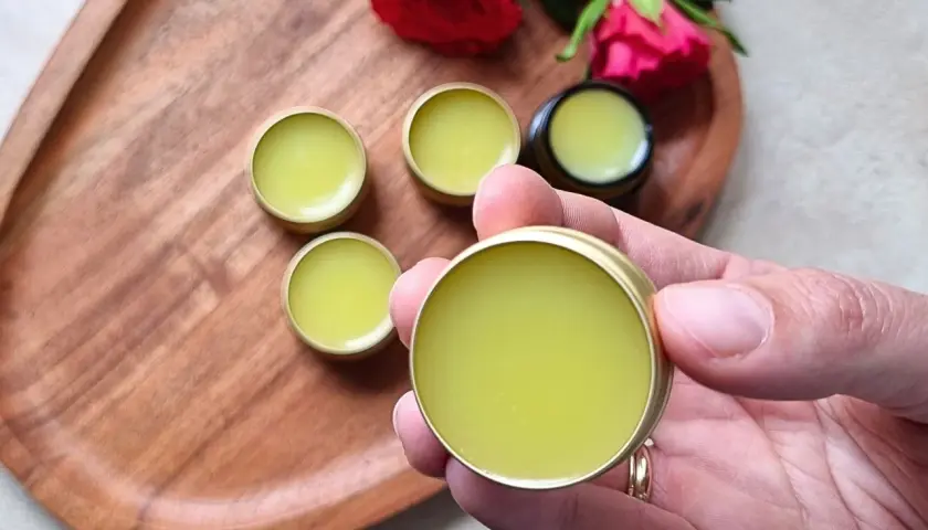 Małe, złote pojemniczki z zielonym balsamem, idealne do domowej produkcji perfum. Różane akcenty dodają uroku.