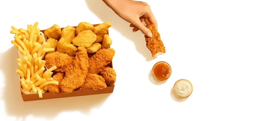Pudełko McDonald's z kurczakiem, frytkami i sosami.