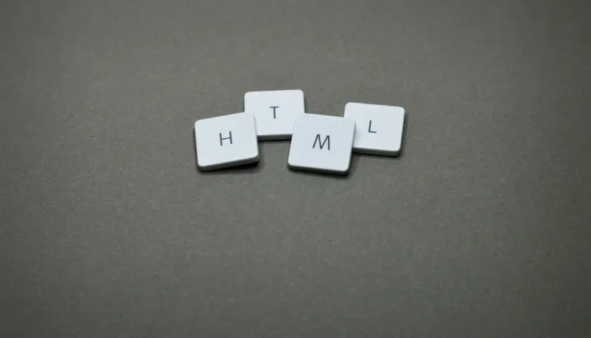 Klocki z literami H, T, M, L układają się w słowo HTML, klucz do tego, jak pisać strony w HTML.