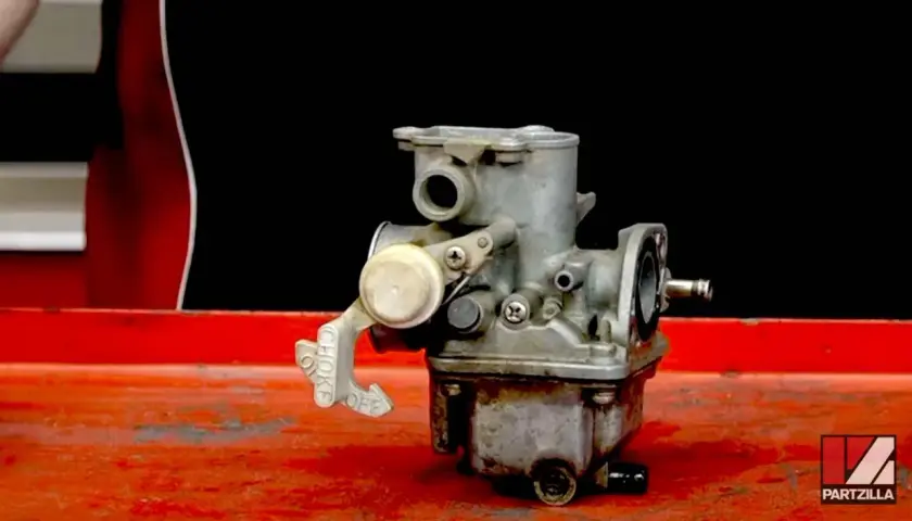 Carburador de moto con palanca de choke. Si la moto se apaga en ralentí, podría ser un problema aquí.