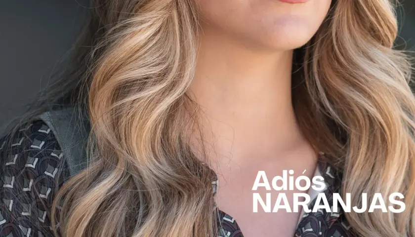 Cabello rubio con mechas matizadas, luciendo un estilo fresco y vibrante. "Adiós Naranjas" en texto blanco.