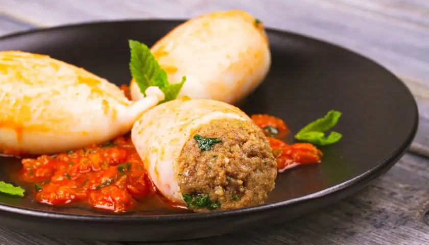 Calamari ripieni in friggitrice ad aria, serviti con salsa rossa e menta fresca. Un piatto gustoso e leggero.