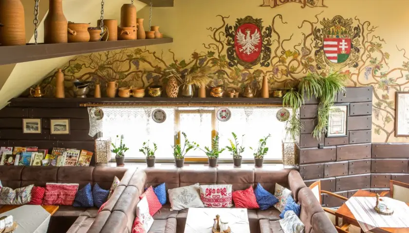 Wnętrze tokaj restauracja węgierska menu. Wygodne kanapy, ozdobne malowidła na ścianie i ceramiczne naczynia tworzą przytulną atmosferę.