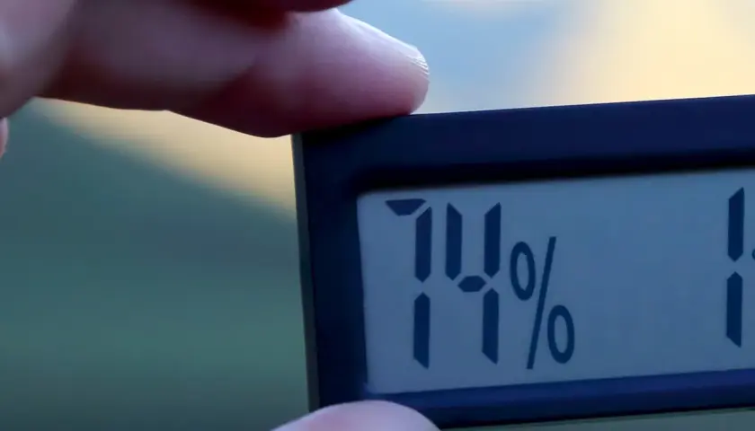 En digital hygrometer visar 74%, vilket indikerar hög luftfuktighet inomhus.