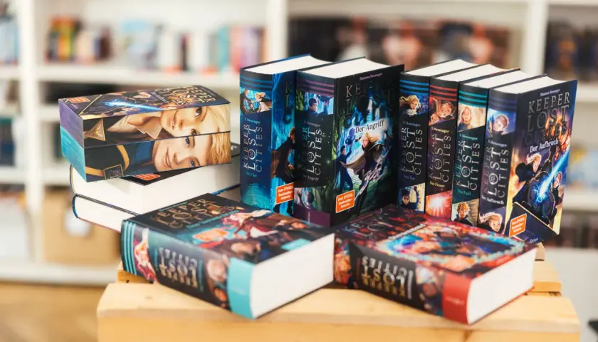 Bücher der Reihe "Keeper of the Lost Cities" in deutscher Reihenfolge, gestapelt und nebeneinander.