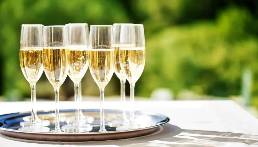 Six flûtes de champagne pétillant sur un plateau argenté, prêtes pour le dessert. Quel champagne pour le dessert ?