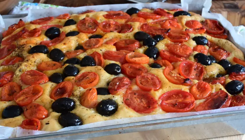 Focaccia con pomodorini e olive nere, un'esplosione di sapori che ricorda la semplicità di un pasto come quello di Rossella, pane e cioccolato.
