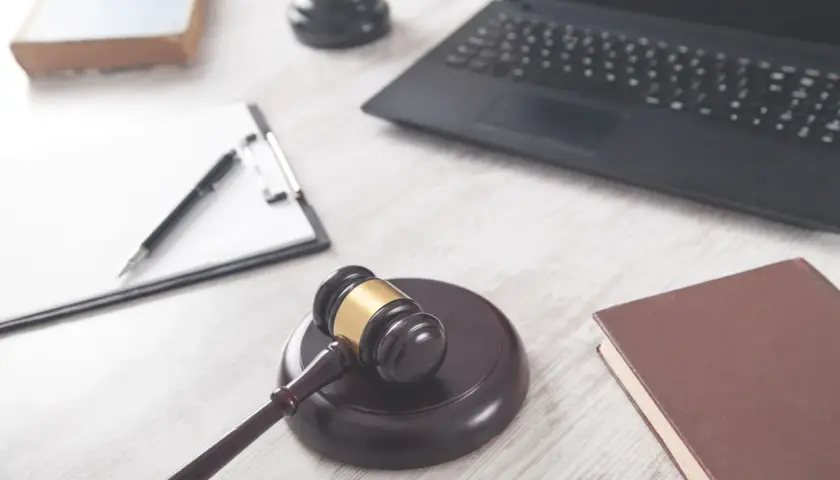 Młotek sędziowski, laptop, notatnik i książka na biurku. Czas na podjęcie decyzji celu publicznego.