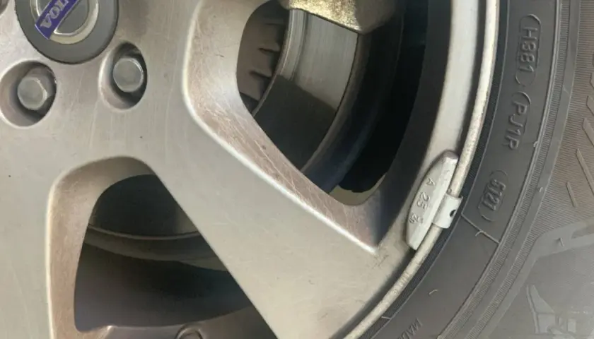 Detalle de una llanta de coche con un plomo de equilibrado de ruedas visible.