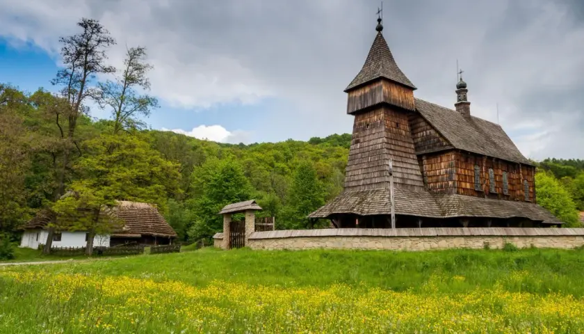 Drewniana cerkiew i chałupa na tle zielonych wzgórz. Największy skansen w Polsce zaprasza do podróży w czasie.