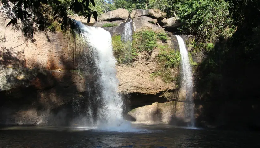 Zwei Wasserfälle stürzen in Khao Yai in einen dunklen Pool. Üppige Vegetation umgibt die Felsen.