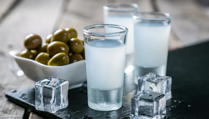 Trzy kieliszki z mlecznym ouzo, kostki lodu i miseczka oliwek. Tak pije się ouzo, by poczuć smak Grecji.
