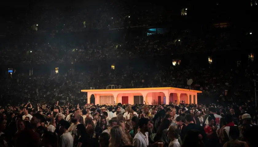 Stor publik på en konsert i Strawberry Arena. En rosa byggnad med gula detaljer står på scenen.