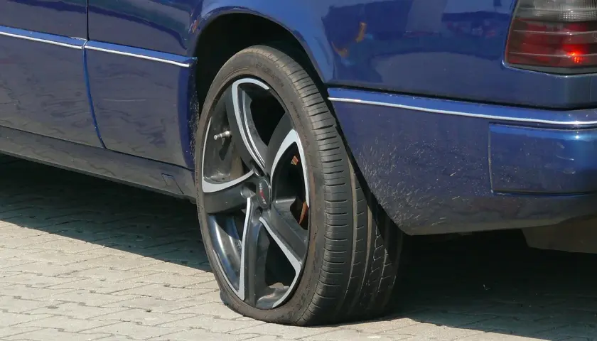 Pneu à plat sur une voiture bleue. Une situation qui pourrait compliquer un recours achat voiture particulier.
