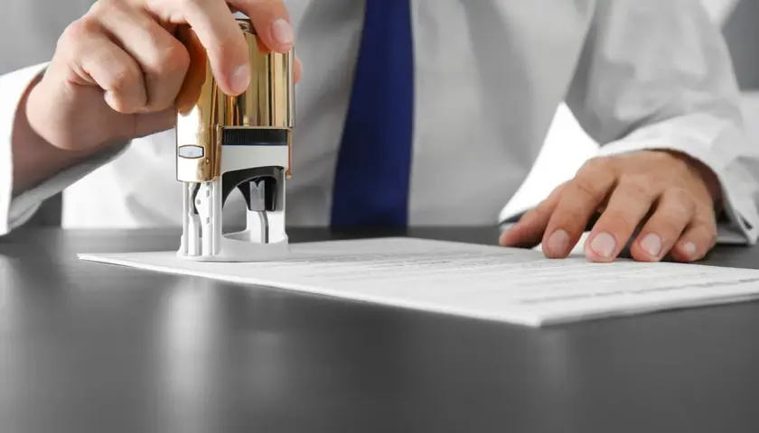 Dłoń z pieczątką nad dokumentem. KNF rekomendacja s. - oficjalne zatwierdzenie.