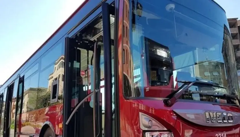 Autobus rosso con porte aperte, riflessi di palazzi sui vetri. Forse l'ultima metro della giornata, ma è un bus.
