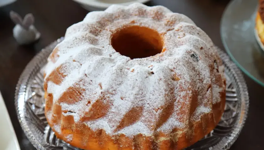 Puszysta babka drożdżowa, jak z babcinego przepisu, oprószona cukrem pudrem, na kryształowej paterze.