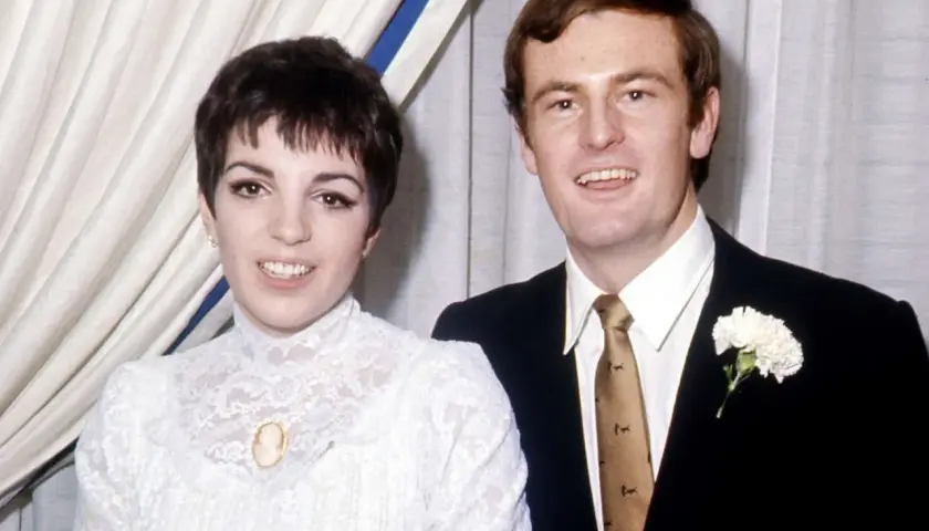 Liza Minnelli och hennes make på bröllopsdagen. Hon bär en vit spetsklänning och han en mörk kostym med en vit nejlika.