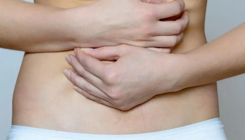 Mani che stringono l'addome, indicando il disagio delle coliche gassose.
