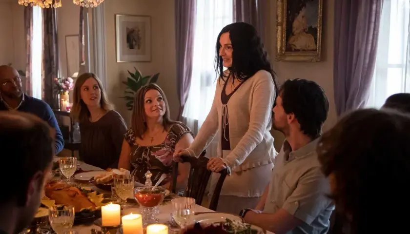 En familj samlas runt ett middagsbord, kanske för en högtidlig stund som i Knutby (tv-serie). Ljusen flimrar och maten är framdukad.