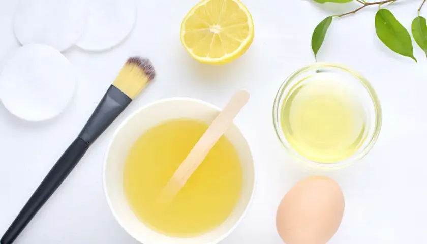 Ingredientes para una mascarilla casera para el pelo: huevo, limón, aceite y aplicador.