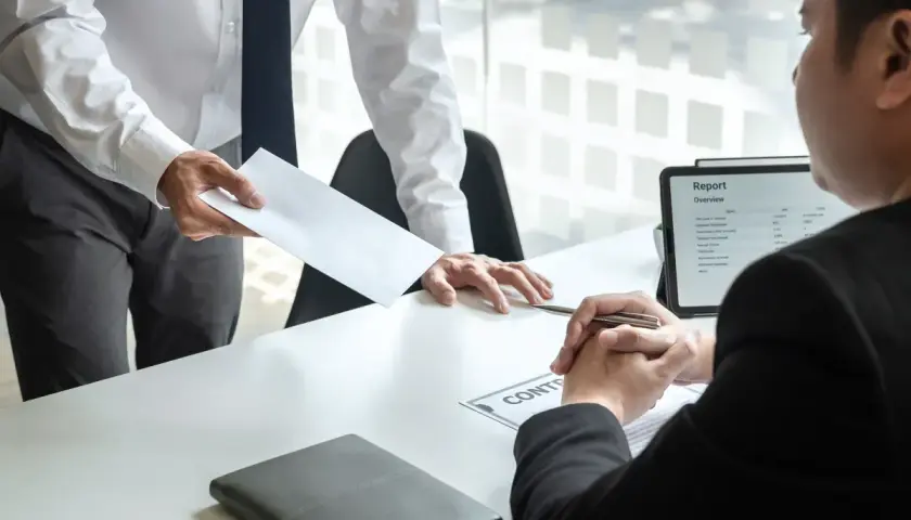 Wręczenie koperty z dokumentem, na którym widnieje napis "CONTRACT". Prawdopodobnie to umowa na czas określony.