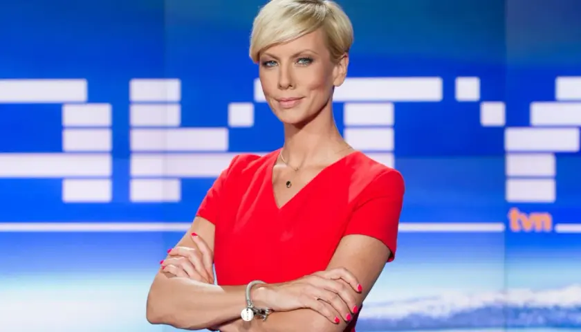 Małgorzata Łaszcz, dziennikarka, w czerwonej sukience, z krótkimi blond włosami, na tle studia TVN.