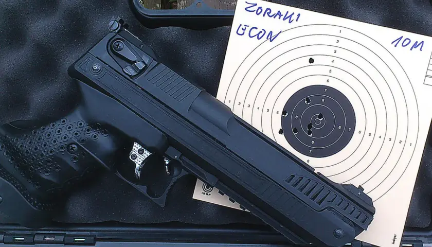 Pistolet Zoraki HP-01 Ultra obok tarczy strzeleckiej z widocznymi trafieniami na 10 metrów.