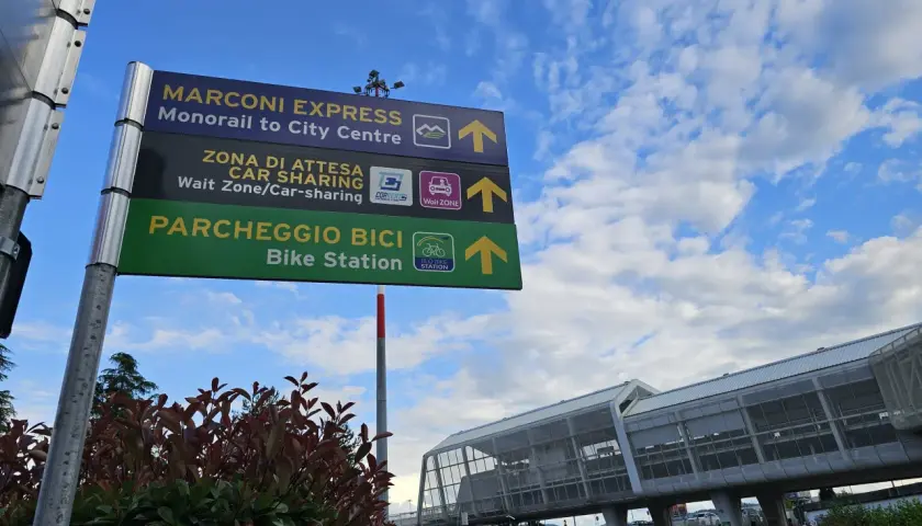 Znaki na lotnisku Bolonia wskazują drogę do Marconi Express, car sharingu i parkingu rowerowego.
