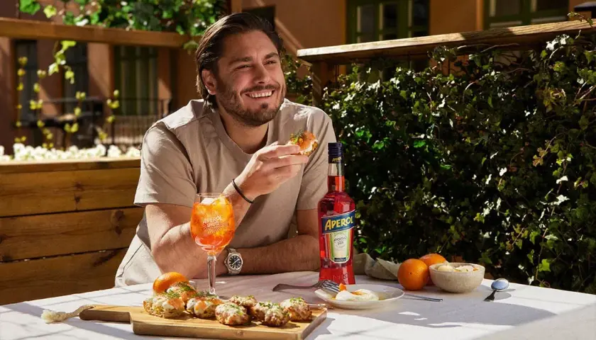 Man njuter av en Aperol Spritz och tilltugg utomhus.