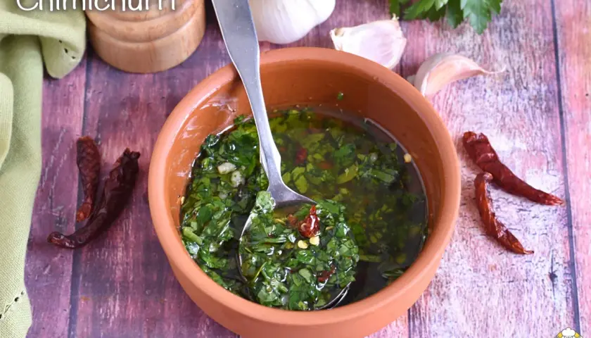 Salsa chimichurri fresca in ciotola di terracotta, con aglio, peperoncino secco e prezzemolo.