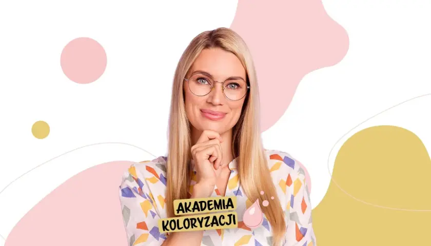Kobieta z chłodnym blondem i okularami, z ręką na podbródku, uśmiecha się. Na jej bluzce widnieje napis "AKADEMIA KOLORYZACJI".