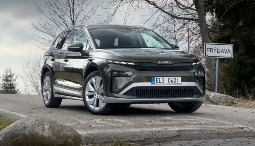 Zielony Skoda Enyaq na drodze, obok znaku "FRÝDAVA". Sprawdź atrakcyjną skoda enyaq cena.