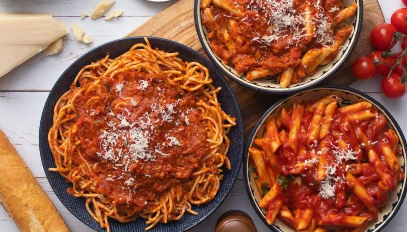 Pyszny obiad bez mięsa: spaghetti i penne w sosie pomidorowym, posypane parmezanem. Idealne dla wegetarian.
