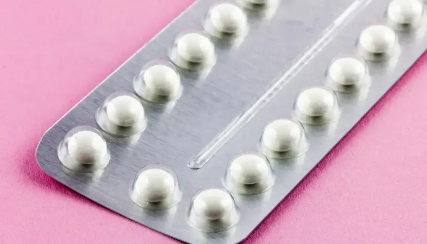 Eine Blisterpackung mit weißen Pillen auf rosa Untergrund. Die Pillen sind bereit, um sie durchzunehmen.