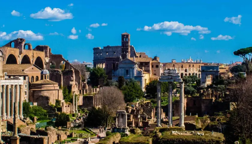 Il Foro Romano, un'istantanea di un viaggio a Roma 48h. Rovine antiche, il Colosseo e il cielo azzurro con nuvole bianche.