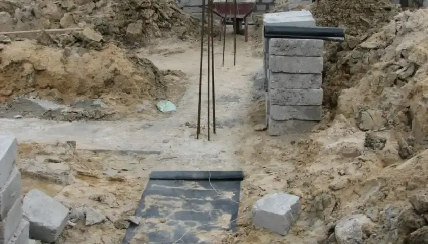 Wykonano wykopy pod fundamenty. Widać zbrojenie, betonowe bloczki i ziemię.