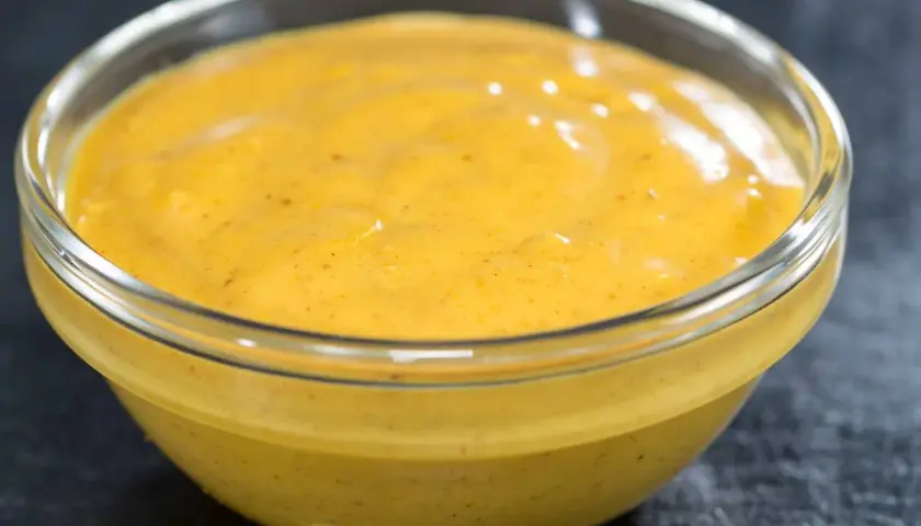 Gęsty, żółty sos curry na mleczku kokosowym w szklanej miseczce. Dlaczego sos się warzy i jak to naprawić?