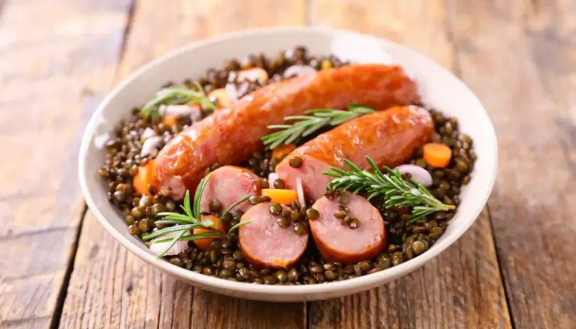 Saucisse lentille Cookeo : un plat réconfortant avec des saucisses savoureuses sur un lit de lentilles, carottes et romarin.