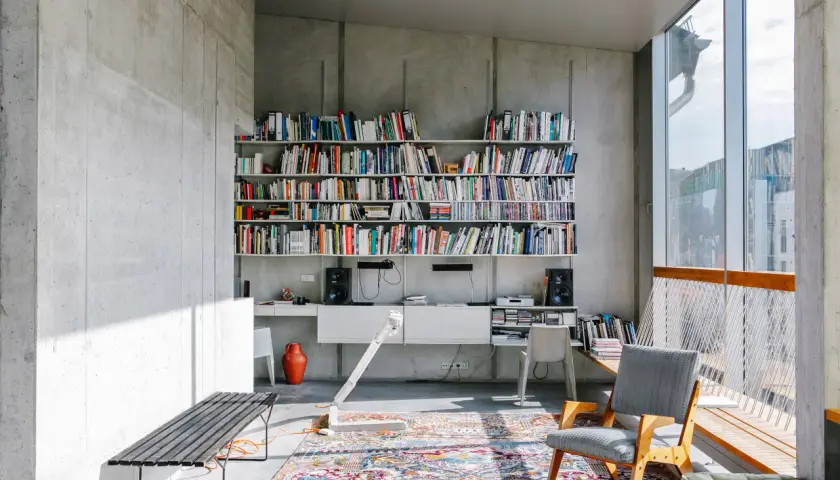 Ein bunter, detailreicher Perserteppich bildet einen warmen Kontrast zur kühlen Betonarchitektur und zeigt, wie man einen Perserteppich modern kombinieren kann.