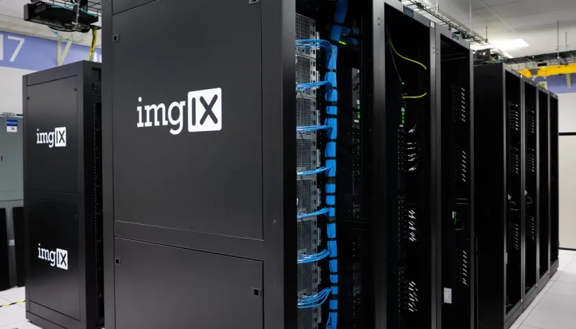 Des racks de serveurs noirs, dont un avec le logo "imgIX", remplis de câbles bleus et jaunes. C'est un peu ça, un serveur : le cœur de l'internet.