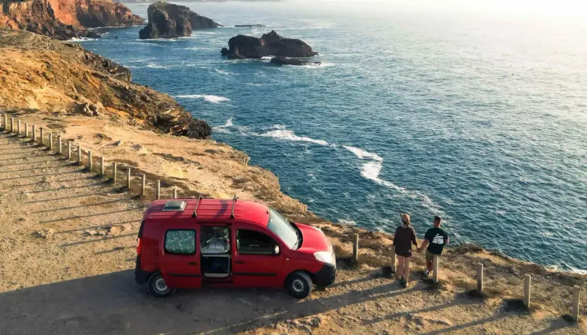 Para podróżuje kamperem po Portugalii, podziwiając skaliste wybrzeże i ocean.